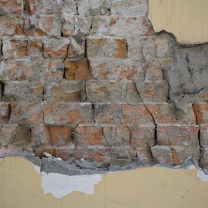 Damaged brick wall with peeling plaster