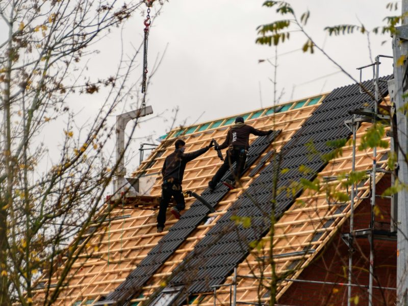 Construction workers installing roofing materials on a house.